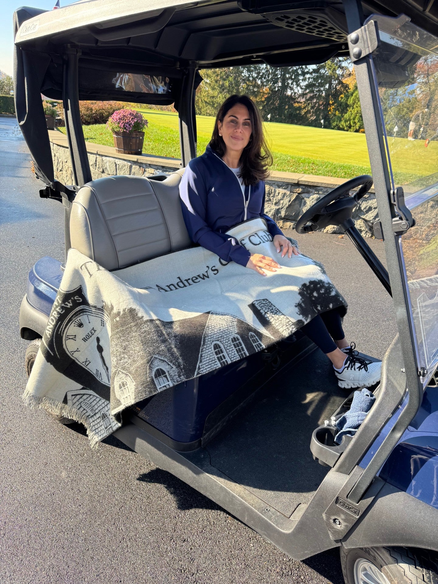 Woman sitting in a golf cart with a personalized blanket on the seat